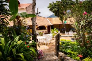 a garden with a table and chairs in front of a house at Hostal Jardín Escondido in Vilcabamba