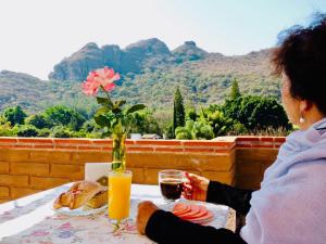 a woman sitting at a table with a glass of orange juice at Hotel Boutique Jardín de Flores in Tlayacapan