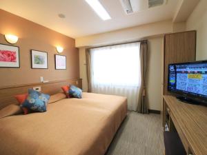 a hotel room with two beds and a flat screen tv at Kyoto Hana Hotel in Kyoto