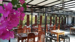 a restaurant with wooden tables and chairs and pink flowers at Bagan Nova in Bagan