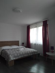 a bedroom with a bed and a window with red curtains at Casa Anca in Bistriţa