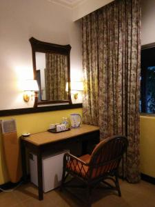 a desk in a hotel room with a mirror and a chair at Motel Desa in Kuala Terengganu