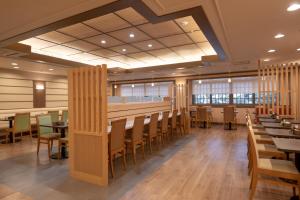 Ginza Capital Hotel Akane في طوكيو: غرفة طعام مع طاولات وكراسي خشبية