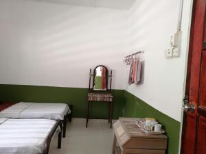Habitación con 2 camas, espejo y mesa. en Delimah guesthouse en Kuala Tahan