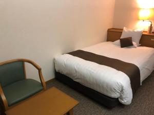 Habitación de hotel con cama y silla en Daiichi Inn Ikebukuro, en Tokio