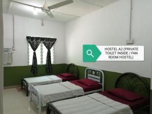 Habitación con 4 camas y ventilador de techo. en Delimah guesthouse, en Kuala Tahan