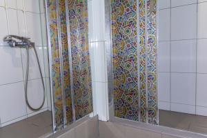 La salle de bains est pourvue d'une douche et d'une porte en verre colorée. dans l'établissement AHOSTEL, à Iekaterinbourg