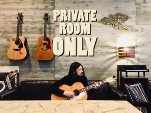 a man playing a guitar in a room with guitars at Kangaroo Hotel in Tokyo