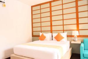 a bedroom with a large white bed with orange pillows at Apple Villa & Suite Seminyak in Seminyak