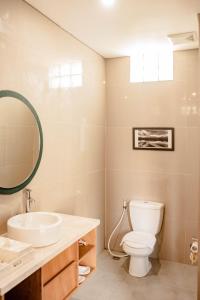 a bathroom with a toilet and a sink and a mirror at Apple Villa & Suite Seminyak in Seminyak