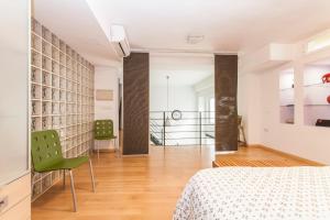 sypialnia z łóżkiem i dwoma zielonymi krzesłami w obiekcie LF PARKING INCLUIDO Amplio Loft en Barrio Santa Cruz w Sewilli