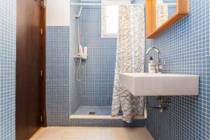 W wyłożonej niebieskimi kafelkami łazience znajduje się umywalka i prysznic. w obiekcie LF PARKING INCLUIDO Amplio Loft en Barrio Santa Cruz w Sewilli