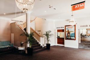 a lobby with a staircase and potted plants at Port Macquarie Hotel in Port Macquarie