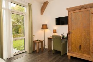 a hotel room with a desk and a window at Hoevehotel 'Hof Christina' in Vrouwenpolder