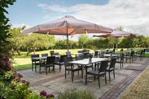 a patio with tables and chairs and umbrellas at Hoevehotel 'Hof Christina' in Vrouwenpolder