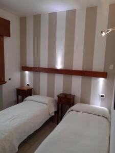 two beds in a room with striped walls at Sweet Appartment di Guido in Peschiera del Garda