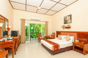 a hotel room with a bed and a desk and a television at Heritage Hotel in Anuradhapura