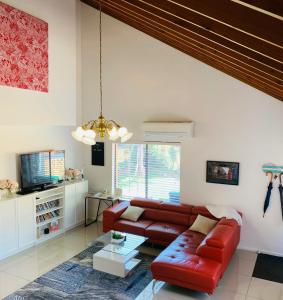 a living room with a red leather couch and a tv at Central Tranquility in Orange
