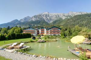 un complejo con un lago con sillas y un hotel en Alpenhotel Speckbacher Hof, en Gnadenwald