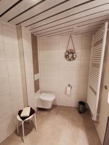 uma casa de banho com um WC e uma cadeira. em Ferienwohnungen Traumlage em Kronsgaard