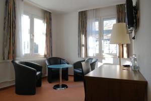 Pokój hotelowy z krzesłami, stołem i biurkiem w obiekcie Parkhotel Goldlinde w mieście Bodenwerder