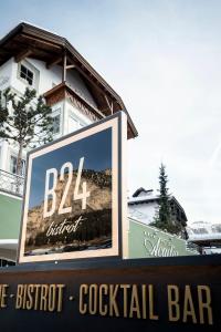 un cartello per un cocktail bar con sconto bkk di fronte a un edificio di Hotel Acadia - Adults Mountain Home a Selva di Val Gardena