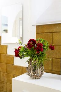 a vase filled with red roses sitting on a table at Palermo Central Holiday in Palermo +16 photos