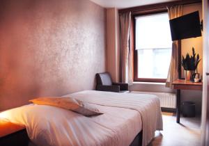 a bedroom with a bed and a window and a chair at Hotel Rubens in Ostend