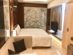 a bedroom with a bed and a couch and a tv at Hotel Maple Taiwan Boulevard in Taichung