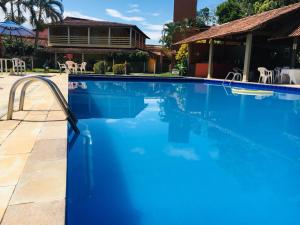 - une piscine d'eau bleue en face d'une maison dans l'établissement Hotel Pousada Caminho da Praia, à Guarapari