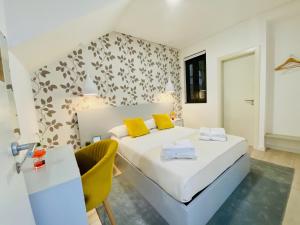 1 dormitorio con cama con almohadas amarillas y escritorio en Family Hostel Costa Nova en Costa Nova