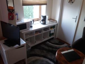 ein Wohnzimmer mit einem Schreibtisch, einem TV und einem Fenster in der Unterkunft Pensionszimmer Lützowzimmer in Lübeck