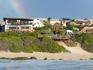 une maison sur la plage avec un arc en ciel dans l'établissement African Perfection 1, à Jeffreys Bay