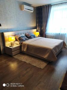 a bedroom with a bed with two lamps and a window at Apartment on Lenina 49 in Salihorsk