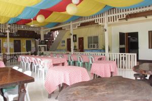 Oasis Resthouse في San Agustin: مطعم به طاولات وكراسي وسقف ملون