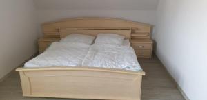 un letto in legno con lenzuola e cuscini bianchi di Fewo Mehrwald a Korbach