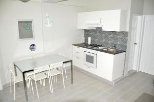 une cuisine avec des armoires blanches et une table et des chaises dans l'établissement Caribe Apartament S&D el castillo dominicus Apartamento #9, à Bayahibe