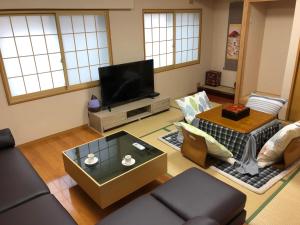 ein Wohnzimmer mit einem Sofa und einem TV in der Unterkunft 大阪西九条stay in Osaka
