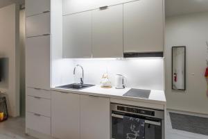 a white kitchen with white cabinets and a sink at Tuomas´ luxurious suites, Hilla in Rovaniemi