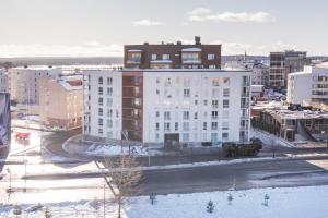 a large white building in a city with snow at Tuomas´luxurious suites, Davvi in Rovaniemi