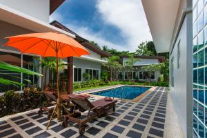 an orange umbrella and chairs next to a swimming pool at Irawan House in Ao Nang Beach