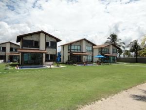 Aominium-Gebäude mit Rasen davor in der Unterkunft BANGALÔ PRAIA DE MURO ALTO/PORTO DE GALINHAS in Porto De Galinhas