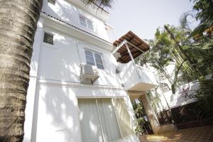 a white house with a door and a palm tree at Victoria Villa in Sinquerim