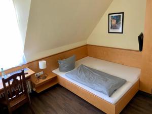 a small bedroom with a bed and a desk at Münchner Hofbräu Coburg in Coburg