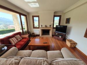 a living room with a couch and a tv at Arroes Village And Pool - Villa con piscina privada in Villaviciosa