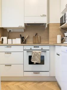 La cuisine est équipée de placards blancs et d'un four. dans l'établissement Cityview Design Apartment Amber, à Lahti