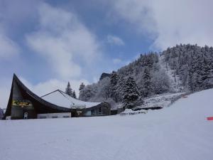 un bâtiment dans la neige à côté d'une montagne dans l'établissement BIENVENUE AU LIORAN, à Le Lioran