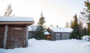 une cabane en rondins dans la neige à côté d'un bâtiment dans l'établissement Rukan Villa Nuotta, à Ruka