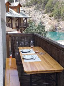 a wooden table with a glass of wine on a balcony at Appartement du lac in Guillestre