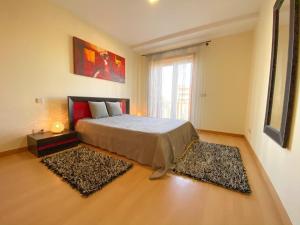 a bedroom with a bed and two rugs on the floor at Sol Poente Praia Apartment in Apúlia